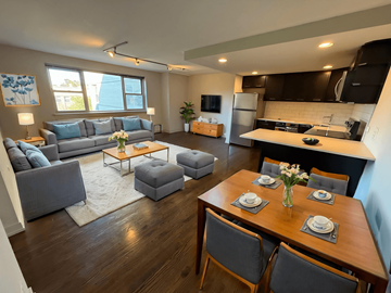 Chicago apartment for rent - A modern living room with a grey couch and a wooden dining table.