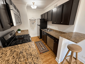 Chicago apartment for rent - A kitchen with black cabinets and a granite countertop.