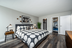 Chicago apartment for rent - A bedroom with a bed, nightstand, and a plant at The Bryn - 5600 N Sheridan Rd Apartments, Illinois, 60660