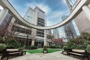 Vancouver apartment for rent - A modern building with a glass facade and a circular walkway in front.