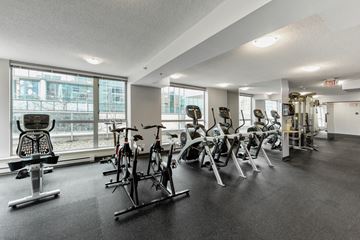 Vancouver apartment for rent - A gym with a row of exercise bikes and a weight rack.