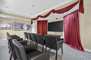 Room with a row of black chairs and red curtains