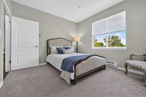 Lakewood apartment for rent - A bedroom with a large bed and a window overlooking a tree.