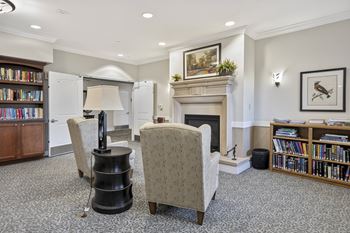 Library reading nook room with a fireplace, two chairs, and a bookshelf