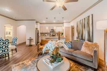 Carrollton apartment for rent - A living room with a grey couch and a coffee table with a vase of flowers on it.