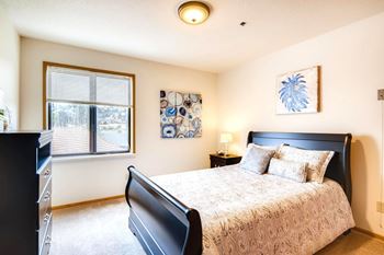 A bedroom with a large bed and a window with blinds.