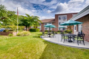 A patio with a table and chairs is surrounded by a grassy area.
