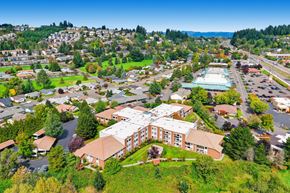 King City apartment for rent - A large building with a pool in the middle of a parking lot. at King City Senior Village Apartments, King City, OR