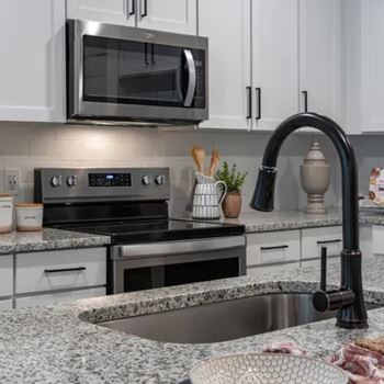 A modern kitchen with granite countertops and stainless steel appliances.