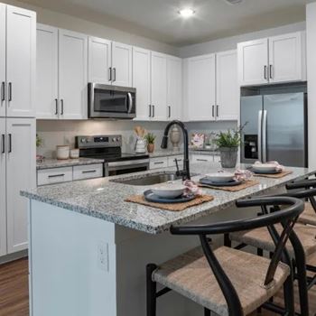A kitchen with granite countertops and white cabinets.