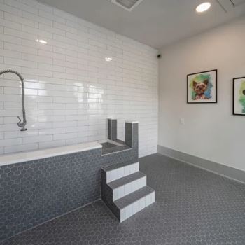 A bathroom with a white tiled wall and a grey tiled floor.
