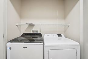 Vadnais Heights apartment for rent - A white Washgood washing machine sits next to a white shelf in a laundry room.
