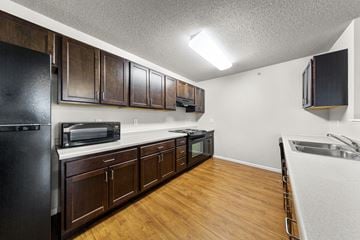 Rochester apartment for rent - A kitchen with dark wood cabinets and a black refrigerator.
