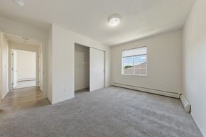 Rochester apartment for rent - A spacious room with a carpeted floor and a window showing a building outside.