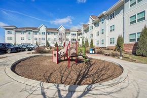 Newport apartment for rent - A playground with a red swing set in front of apartment buildings.