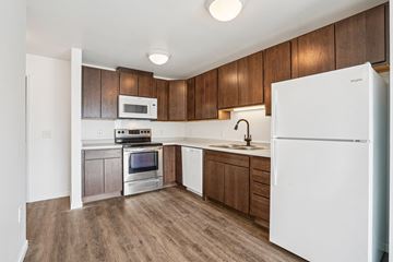Eagan apartment for rent - A white refrigerator is in the corner of a kitchen with wooden cabinets.