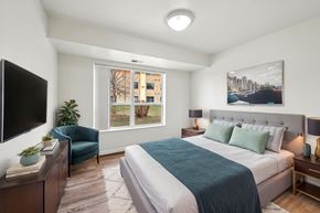 Rochester apartment for rent - A bedroom with a large bed and a flat screen TV.