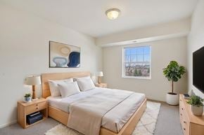 Forest Lake apartment for rent - A bedroom with a large bed, a nightstand with a lamp, and a painting on the wall.