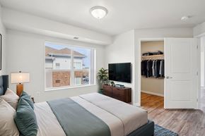 Shakopee apartment for rent - A bedroom with a large bed and a window overlooking a house.