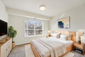 Bloomington apartment for rent - A well-lit bedroom with a large bed and a television.