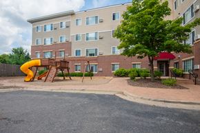 Rochester apartment for rent - a playground in front of an apartment building with a yellow slide
