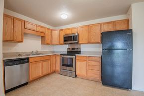 Waconia apartment for rent - A kitchen with wooden cabinets and black appliances.