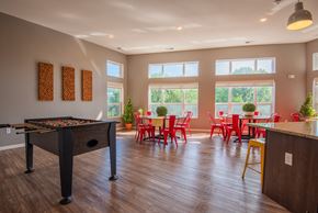 Mounds View apartment for rent - A foosball table is in the middle of a room with red chairs and tables.