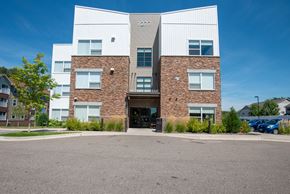 Vadnais Heights apartment for rent - A modern building with a glass entrance and a brick wall.