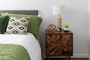 Maple Grove apartment for rent - a bedroom with a bed with green pillows and a night stand with a lamp