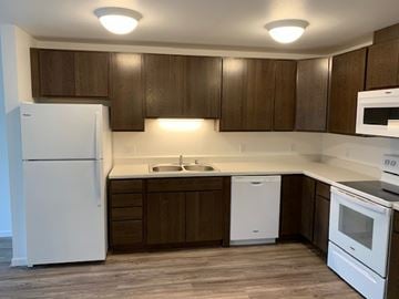 Faribault apartment for rent - A kitchen with white appliances and brown cabinets.