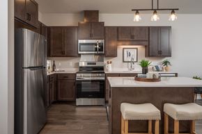 Oakdale apartment for rent - A modern kitchen with a refrigerator, oven, and bar stools.