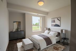 Mankato apartment for rent - A bedroom with a large bed and a window overlooking a green lawn.