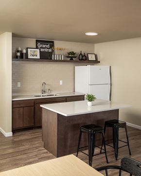 Rochester apartment for rent - A kitchen with a white fridge and brown bar stools.