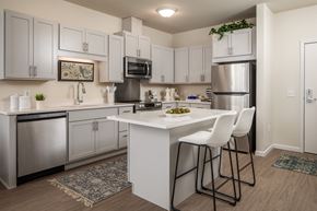 Burnsville apartment for rent - A kitchen with white cabinets and a white island with two chairs.