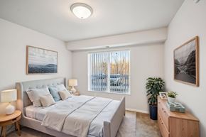 Savage apartment for rent - A bedroom with a large bed, a nightstand, and a window with blinds.