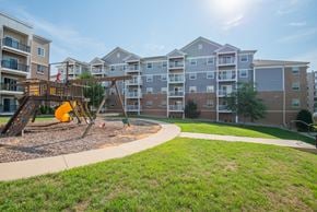 Rochester apartment for rent - a playground with a swing set in front of an apartment building