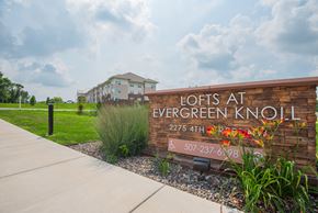 Faribault apartment for rent - A brick sign that says Lofts at Evergreen Knoll in front of a building.