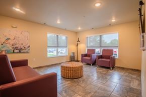 Faribault apartment for rent - A living room with a large painting, two chairs, and a wicker ottoman.