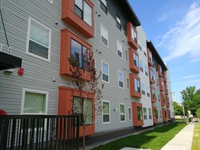 Saint Paul apartment for rent - A tree with red leaves is in front of a grey building with orange trim.