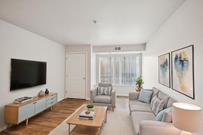 Savage apartment for rent - A living room with a grey couch, a wooden coffee table, and a flat screen TV mounted on the wall.