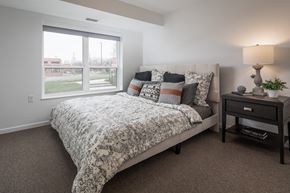 St. Paul apartment for rent - A bedroom with a large bed and a nightstand with a lamp.