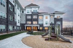 Newport apartment for rent - A playground with a slide and a bench in front of a multi-story residential building.