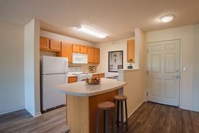 Rochester apartment for rent - a kitchen with white appliances and wooden cabinets and a island with three stools