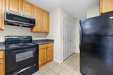 Lake Park apartment for rent - A black refrigerator stands in a kitchen with wooden cabinets and a black stove.