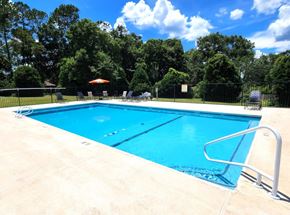 Lake Park apartment for rent - A large blue swimming pool surrounded by a fence and trees.