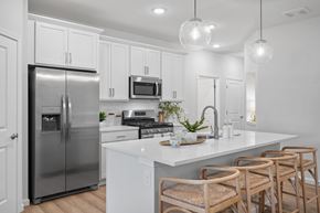 Beavercreek apartment for rent - A modern kitchen with a stainless steel refrigerator, white cabinets, and wooden chairs.