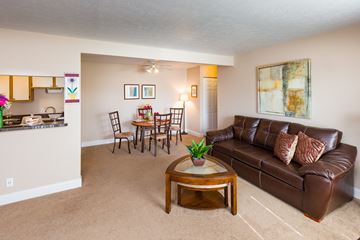 Willowick apartment for rent - A living room with a brown leather couch, a wooden coffee table, and a dining table with chairs.