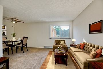 Pittsburgh apartment for rent - A living room with a brown couch and a dining table.