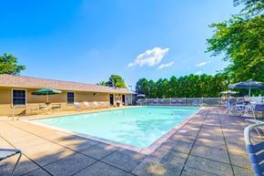 Westlake apartment for rent - A large outdoor swimming pool surrounded by lounge chairs and umbrellas.