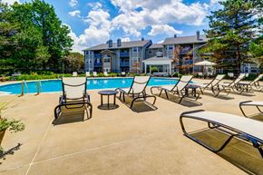 Parma apartment for rent - A pool area with chairs and a table in front of a building.